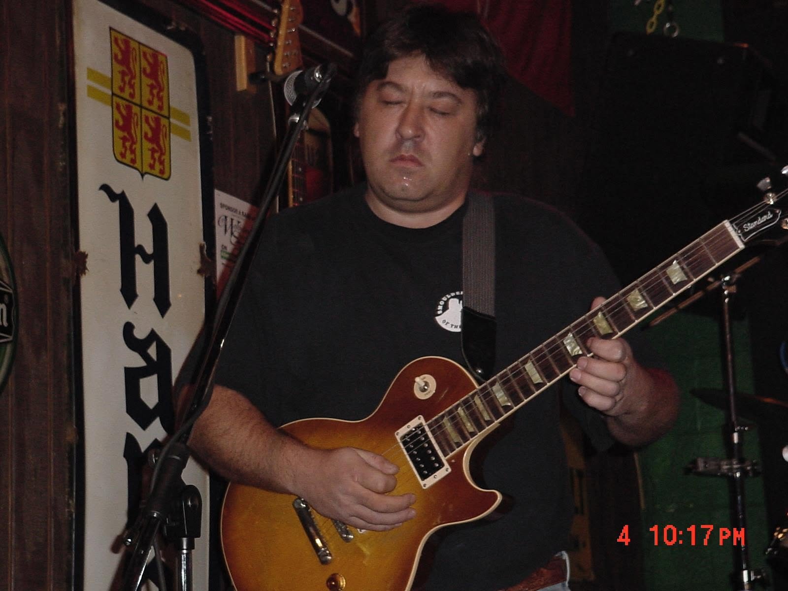 A guitarist playing a sunburst electric guitar on stage